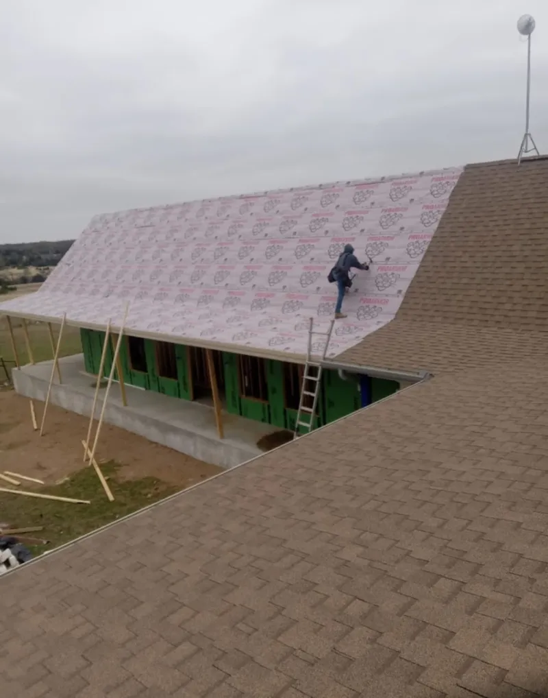 Worker preparing underlayment for a metal roof installation in Artondale
